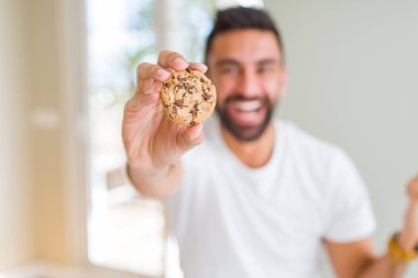 Duygu tezahürat yakışıklı İspanyol man gurur çığlık ve zafer ve başarı çok heyecanlı, kutluyor çikolata kurabiye yemek