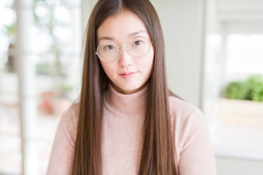 Gevşek ciddi ifade ile yüzünde gözlüklü güzel Asyalı kadın. Basit ve çapraz silah ile doğal