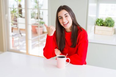 Güzel genç kadın siyah kahve arıyor ve başparmak yanında yukarıyı mutlu yüz ile gülümseyen içme.