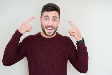 Bir kazak izole üzerinde giyen genç yakışıklı adam arka plan hem el parmak, harika bir fikir ya da düşünce, iyi bellek ile baş gösteren gülümseyen