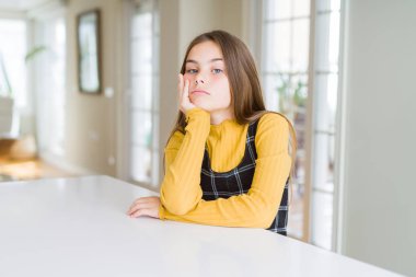 Güzel genç kız çocuk seyir yorgun ve bıkkın ile depresyon sorunları karşılıklı silah olan tablo düşünme üzerine oturan.