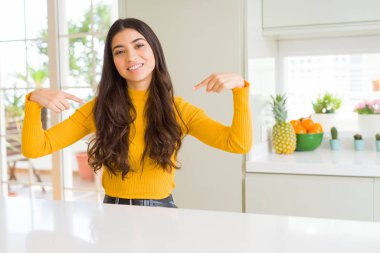 Genç güzel kadın evde yüzünde gülümseme ile kendinden emin görünüyorsun, kendini gururlu ve mutlu parmakları ile işaret beyaz tablo.