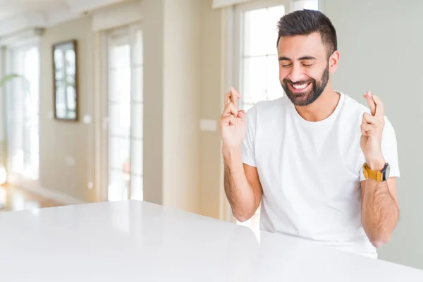 Bonito Hispânico Homem Casual Shirt Branca Casa Sorrindo Cruzando Dedos — Fotografia de Stock