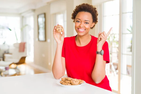 Молодая Африканская Американка Которая Ест Шоколадные Печенья Довольна Указывая Рукой — стоковое фото