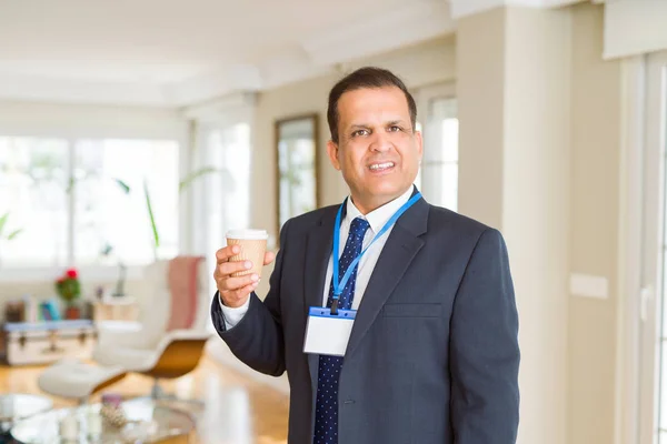 Hombre de negocios de mediana edad bebiendo una taza de café usando identif —  Fotos de Stock