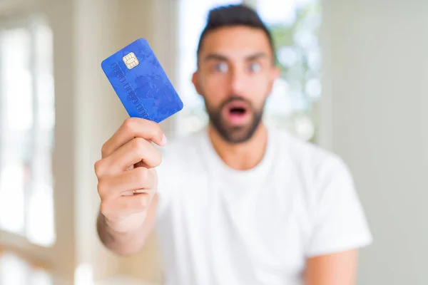 英俊的西班牙男子拿着信用卡吓得惊讶与一个惊喜的脸 害怕和兴奋与恐惧的表情 — 图库照片