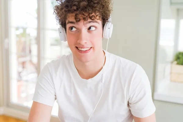 Joven Escuchando Música Usando Auriculares Las Casas Sonriendo Mirando Hacia —  Fotos de Stock