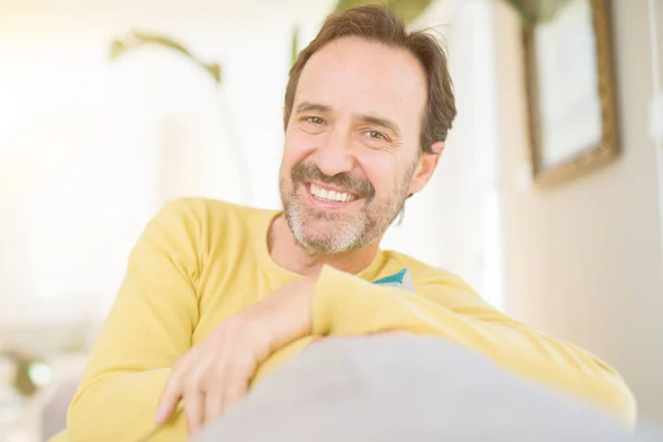 Handsome middle age man sitting on the sofa relaxed and smiling — Stock Photo, Image
