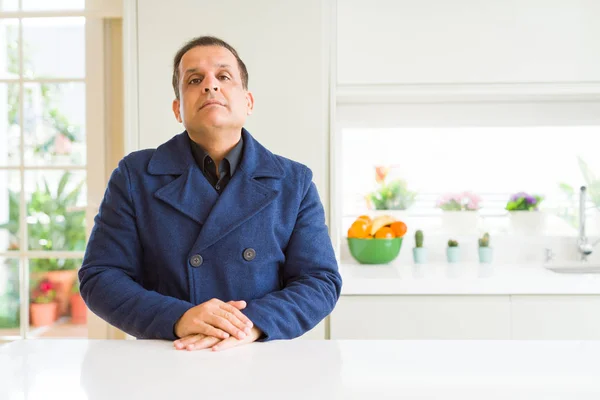 Middle age man sitting at home with serious expression on face. Simple and natural looking at the camera.