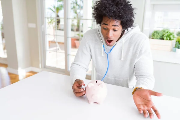 Homem Afro Americano Segurando Estetoscópio Verificando Saúde Financeira Mealheiro Assustado — Fotografia de Stock