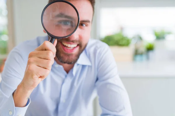 Hombre de negocios guapo sosteniendo lupa cerca de la cara, bi — Foto de Stock