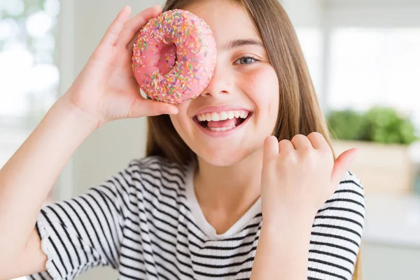 指していると幸せそうな顔を笑顔で側に親指を示す甘いピンクのドーナツを食べて美しい若い女の子子供 — ストック写真