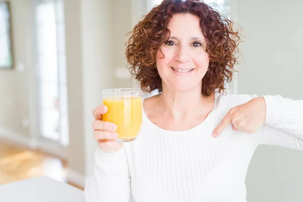年配の女性煮沸自分自身に驚き顔人差し指と新鮮なオレンジ ジュースのガラス — ストック写真