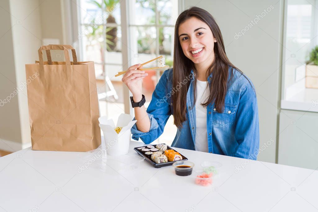 Beautiful young woman eating asian sushi from home delivery with a happy face standing and smiling with a confident smile showing teeth