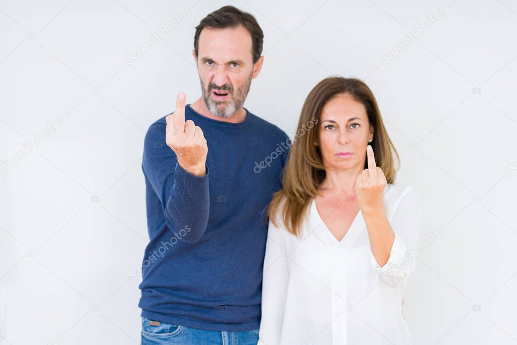 Beautiful middle age couple in love over isolated background Showing middle finger, impolite and rude fuck off expression