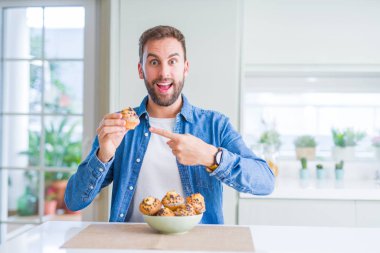 Yakışıklı adam yeme çikolata muffin el ve parmak ile işaret çok mutlu