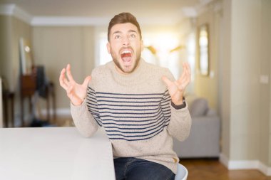 Genç yakışıklı adam evde deli ve deli bağırarak ve agresif ifade ve silah kaldırdı bağırıyor bir kazak giyiyor. Hayal kırıklığı kavramı.