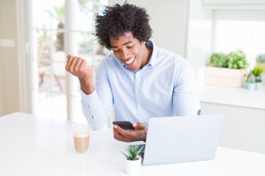 Smartphone ve gurur çığlık ve zafer ve başarı çok heyecanlı, kutluyor dizüstü kullanarak Afrika kökenli Amerikalı iş adamı duygu tezahürat