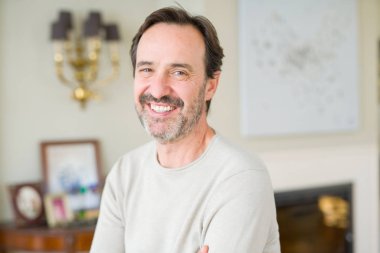 Evde kameraya bakarak gülümseyen yakışıklı orta yaş erkek