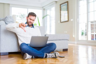 Yakışıklı adam giyen çalışma bilgisayar dizüstü kullanarak kızgın yüzü, eksi işareti aşağı antipati başparmak ile gösterilen, ret kavramı ile