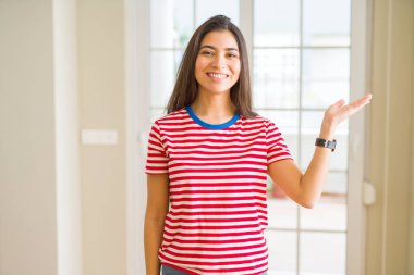 Neşeli sunulması ve kameraya bakarak avucunun ile işaret gülümseyen rahat t-shirt giyen genç güzel kadın.