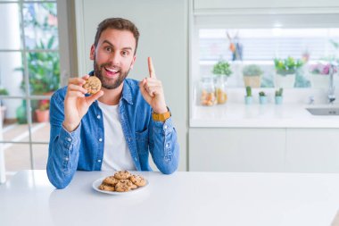 Çerezler bir fikir ya da soru işaret parmağı gülen yüz, bir numara ile sürpriz yakışıklı adam yeme çikolata cips