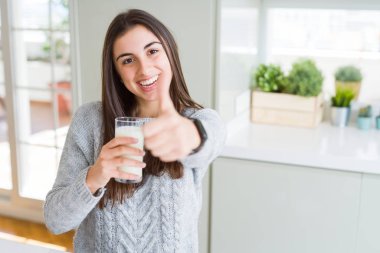 Bir bardak taze süt mutlu ok işareti, başparmak ile parmak, mükemmel işareti yapıyor kocaman bir gülümseme ile içme güzel genç kadın