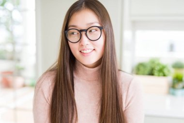 Gözlüklü görünümlü yan ve dik dik bakma uzağa düşünce gülümseyen güzel Asyalı kadın.