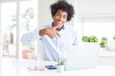 Afrika kökenli Amerikalı iş adamı sürpriz ile dizüstü bilgisayar kullanarak çalışma yüz kendine işaret parmağı