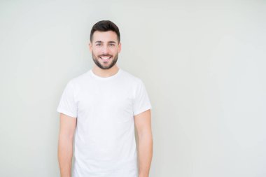 Genç yakışıklı giyiyor rahat beyaz t-shirt yüzünde mutlu ve güzel bir gülümseme ile izole arka plan üzerinde adam. Şanslı kişi.