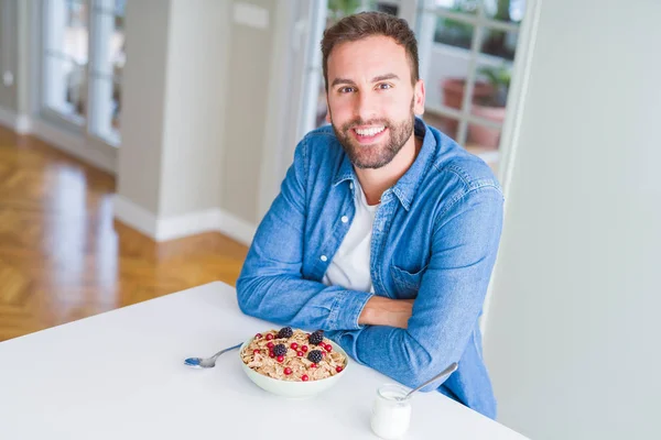 Hombre guapo desayunando comiendo cereales en casa y sonriendo — Foto de Stock