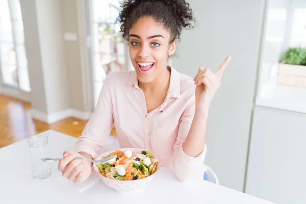 非洲裔美国妇女吃健康的意大利面沙拉非常高兴用手和手指指向一边 — 图库照片