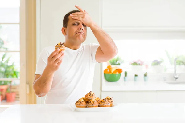 Hombre Mediana Edad Comiendo Magdalenas Chocolate Casa Estresado Con Mano — Foto de Stock