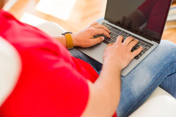 Мужчина средних лет сидит дома на диване с ноутбуком — стоковое фото