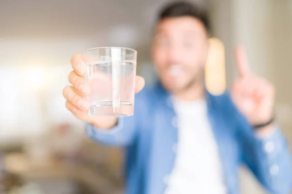 Joven Hombre Guapo Bebiendo Vaso Agua Casa Sorprendido Con Una — Foto de Stock