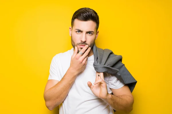 Jovem homem bonito possuindo e modelagem sobre bac isolado amarelo — Fotografia de Stock