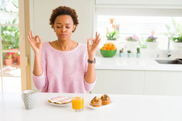 年轻的非洲裔美国妇女吃早餐在早上在家里放松和微笑 闭着眼睛用手指做冥想手势 瑜伽概念 — 图库照片