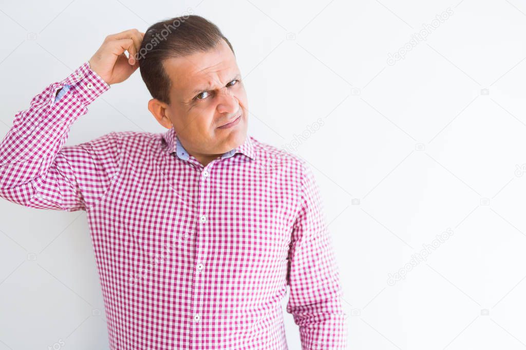Middle age man wearing business shirt over white wall confuse and wonder about question. Uncertain with doubt, thinking with hand on head. Pensive concept.