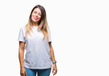 Genç güzel kadın rahat beyaz t-shirt üzerine arka plan seksi bir ifadeyle, neşeli ve mutlu yüzünü kameraya bakarak göz kırpıyor izole.