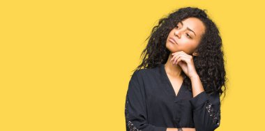 Kıvırcık saçlı zarif el ile çene düşünme hakkında soru, dalgın ifade üzerine elbise genç güzel kız. Düşünceli yüzüyle gülümsüyor. Şüphe kavramı.