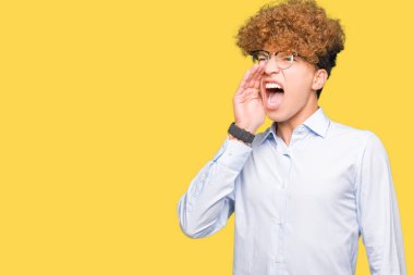 Genç yakışıklı iş adamı ile bağırarak ve ağzı üzerinde el ile yan için çığlık gözlüklü afro. İletişim kavramı.