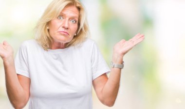 Orta yaş sarışın kadın izole arka plan clueless ve şaşkın bir ifadeyle kollar ve eller kaldırdı. Şüphe kavramı.