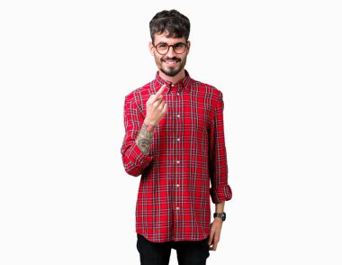 Beckoning gel burada mutlu ve gülümseyerek el davet ile jest arka plan üzerinde gözlük takan genç yakışıklı adam izole