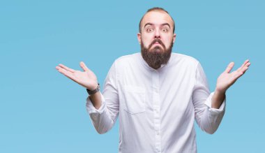 Genç beyaz hipster adam izole arka plan clueless ve şaşkın bir ifadeyle kollar ve eller kaldırdı. Şüphe kavramı.