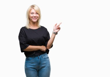 Yüzünde kocaman bir gülümseme ile izole arka plan üzerinde genç güzel sarışın kadın kameraya bakarak yan el ve parmak ile işaret.