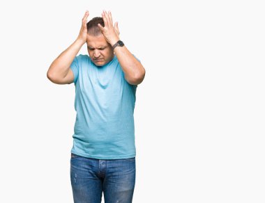 Orta yaş Arap adam mavi tişört giyiyor çünkü umutsuz ve stresli baş ağrısı acı izole arka plan üzerinde ağrı ve Migren. Ellerini kafasına.