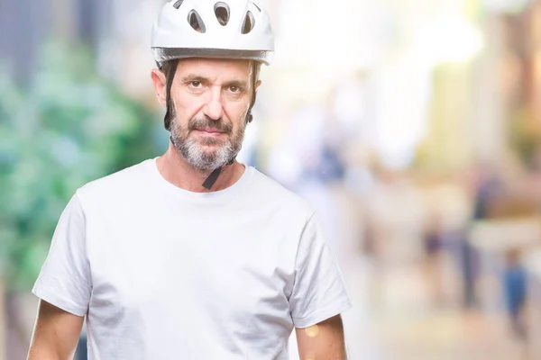 Middle age senior hoary cyclist man wearing bike safety helment isolated background with serious expression on face. Simple and natural looking at the camera.