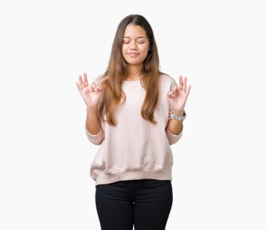 İzole arka plan üzerinde pembe kazak giyen genç güzel esmer kadın dinlenmek ve gülümseyen gözlerle kapalı parmak jestle meditasyon yapıyor. Yoga kavramı.