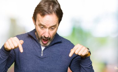 Orta yaş yakışıklı adam kazak giyiyor aşağı reklam, sürpriz yüz ve açık ağız gösterilen parmakları ile işaret