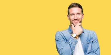 Emin çapraz kollar ve çeneme kaldırdı el ile gülümseme ile kamera seyir kot ceket giyen sakal ve mavi gözlü yakışıklı adam. Pozitif düşünce.